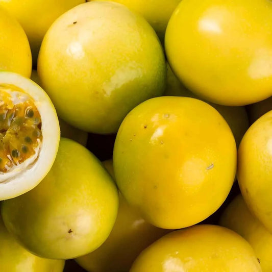 Gros plan de fruits de la passion jaunes entiers et coupés, ingrédient principal du Nectar Passion MONTPELÉ, saveur tropicale intense.