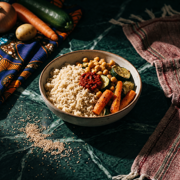 Couscous de fonio : grains clairs, pois chiches, carottes rôties, courgette et sauce rouge dans un bol