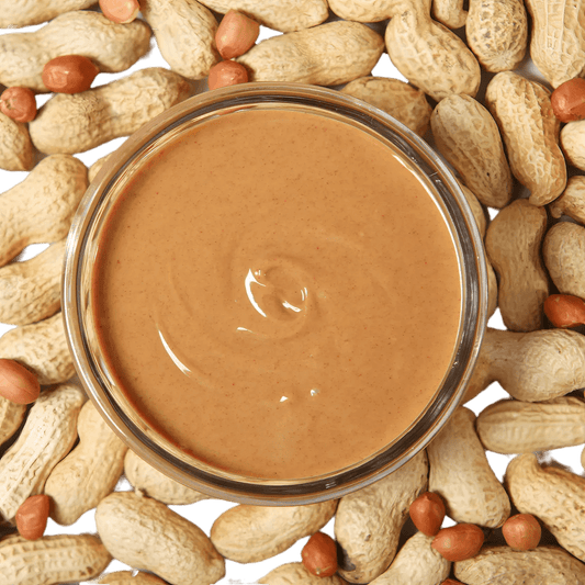 Bol de Beurre de Cacahuète RACINES BIO entouré de cacahuètes entières, mettant en valeur son origine naturelle et bio.