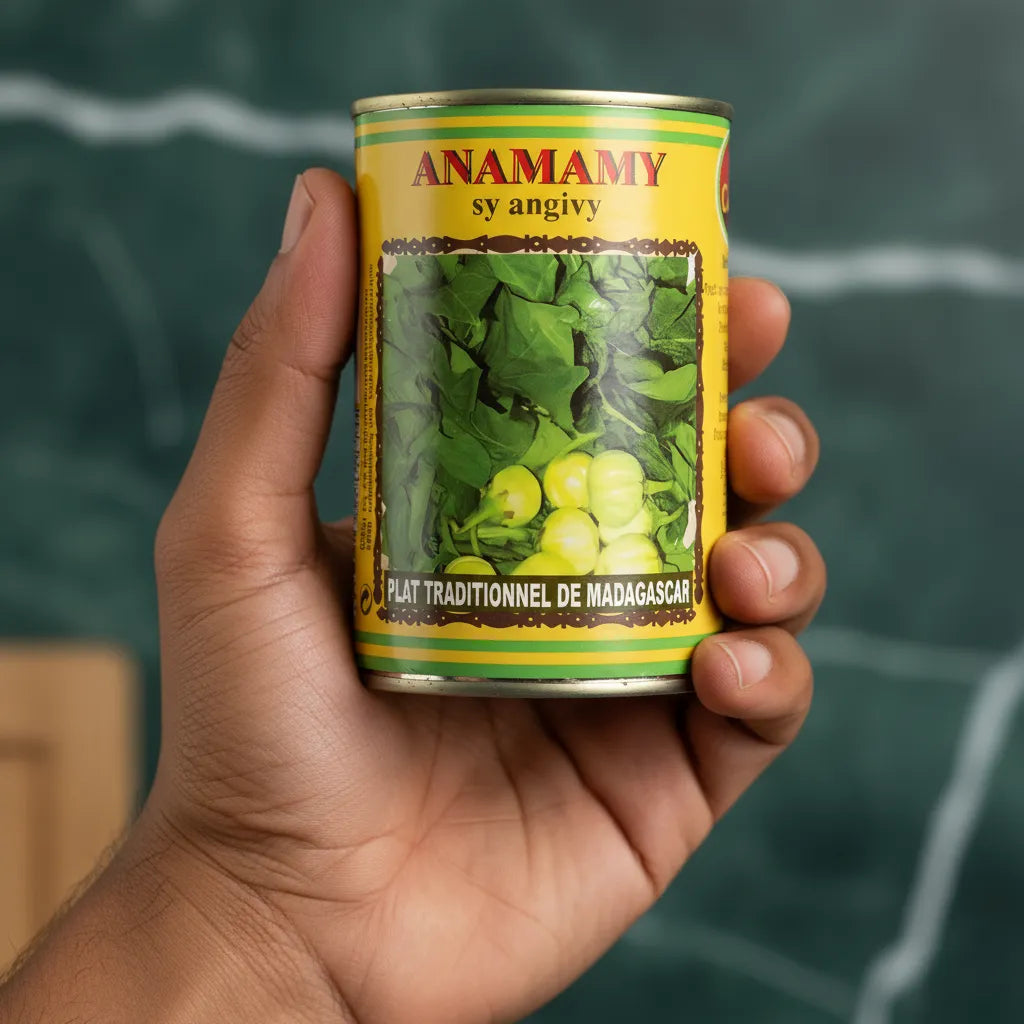 Main tenant une boîte Anamamy Angivy CODAL, conserve de légumes typique de Madagascar, idéale pour plats exotiques en épicerie salée.