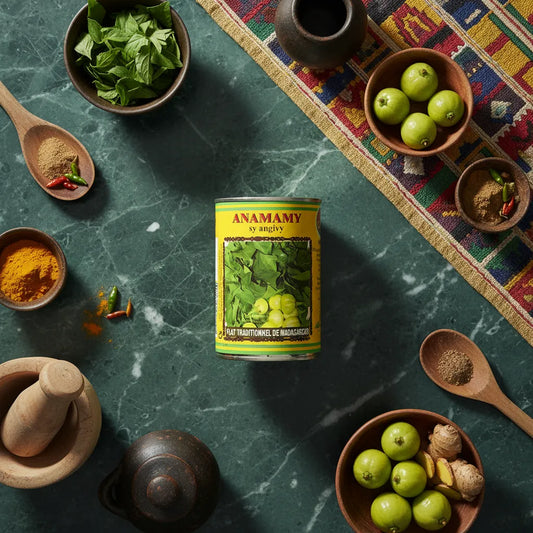 Boîte Anamamy sy angivy CODAL entourée d'ingrédients frais et épices, parfaite pour cuisine malgache traditionnelle et recettes savoureuses.