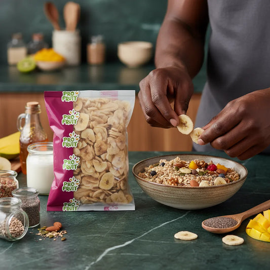 Main ajoutant des chips de banane PROFRUIT à un bol de granola, collation saine et savoureuse à base de fruits secs.