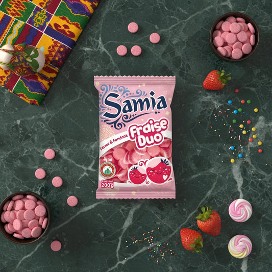 Bonbons fraise duo halal SAMIA sur table en marbre avec fraises, bonbons et décorations, confiserie fruitée pour épicerie sucrée.