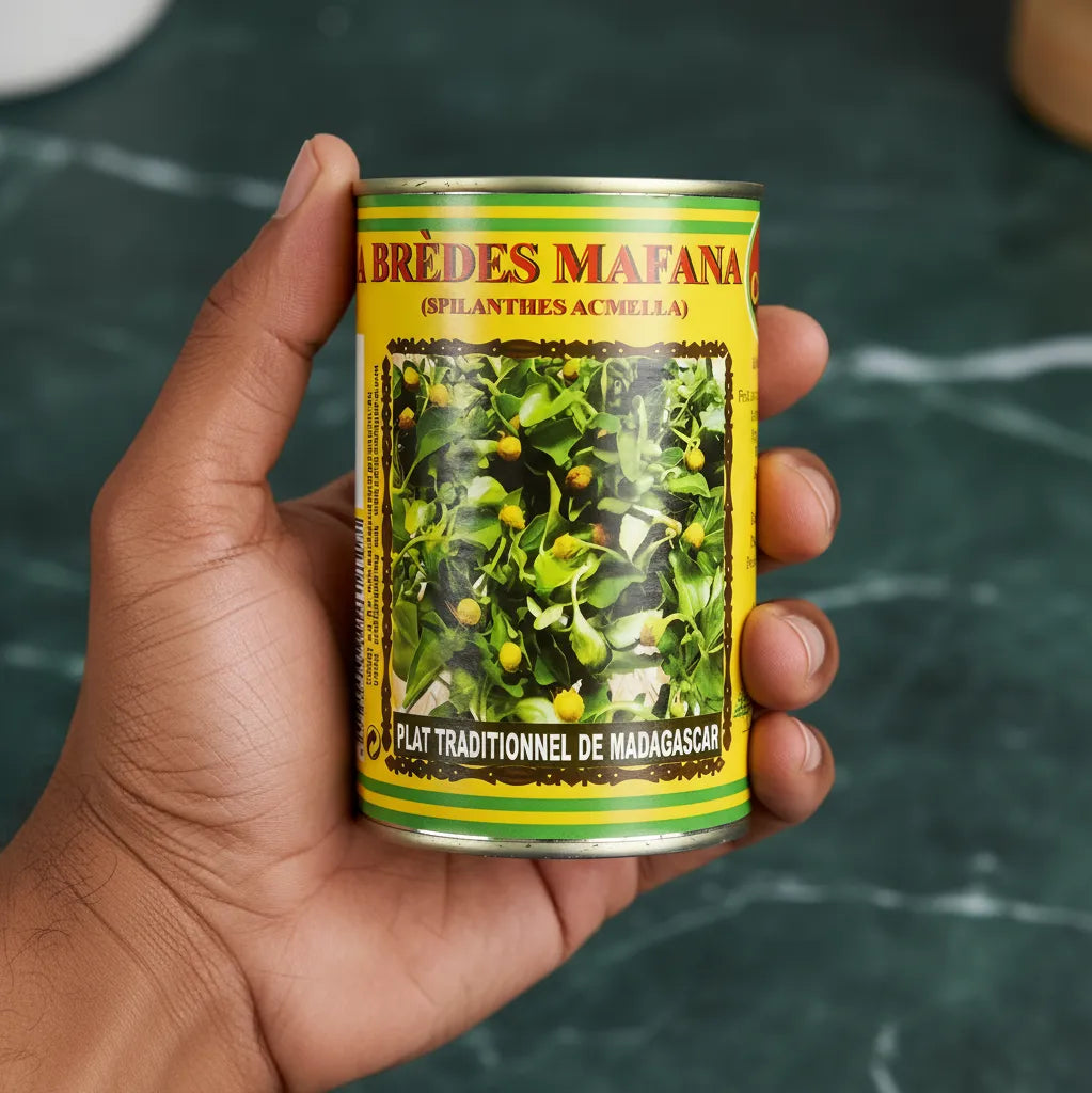 Main tenant une conserve de brèdes mafana CODAL, plante comestible utilisée dans les recettes authentiques de Madagascar.