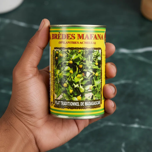 Main tenant une conserve de brèdes mafana CODAL, plante comestible utilisée dans les recettes authentiques de Madagascar.
