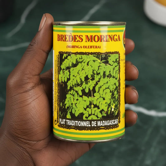 Main tenant une conserve de brèdes moringa CODAL, produit malgache nutritif à base de feuilles de moringa, prêt à cuisiner en toute simplicité.