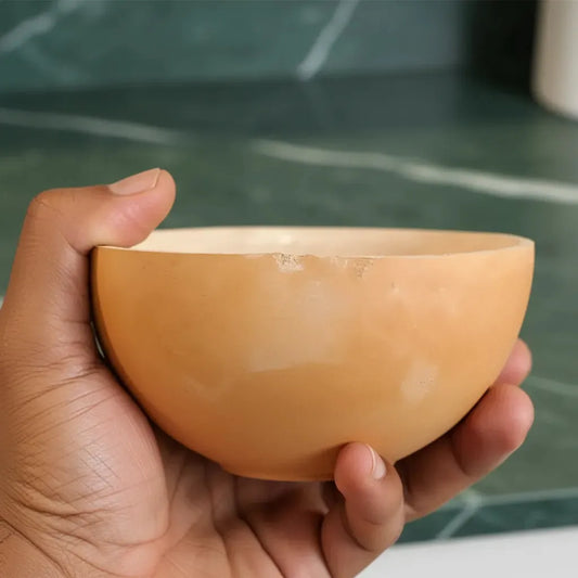 Calebasse Africaine naturelle tenue à la main, accessoire traditionnel de cuisine en matériau naturel, idéale pour un usage quotidien.