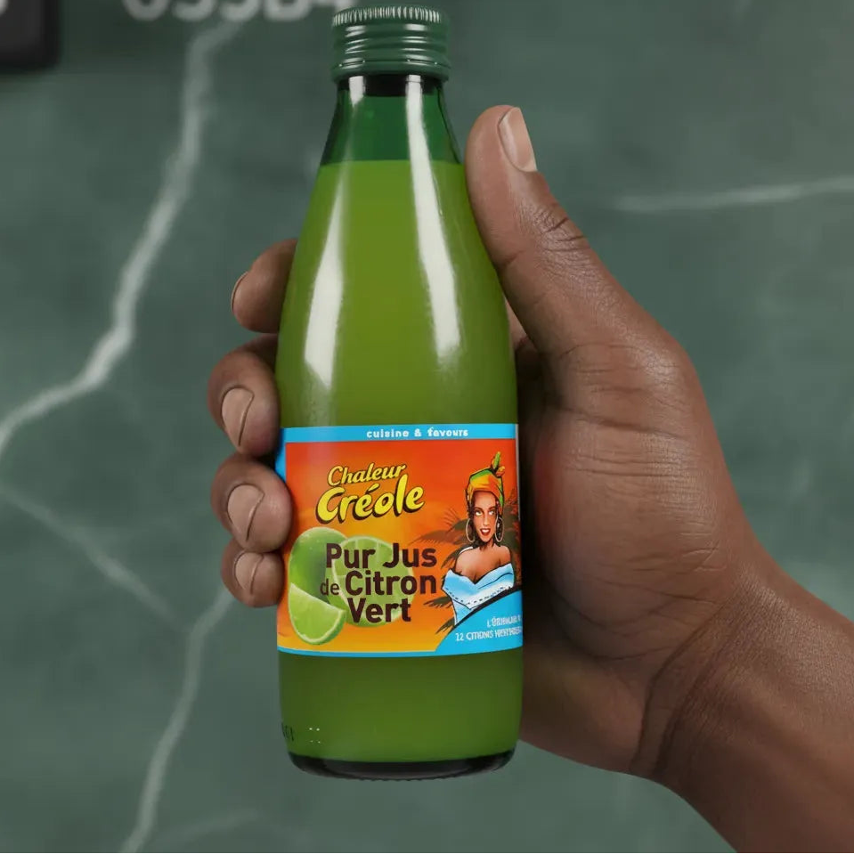 Main tenant une bouteille de jus de citron vert CHALEUR CRÉOLE, condiment incontournable pour relever plats et boissons.