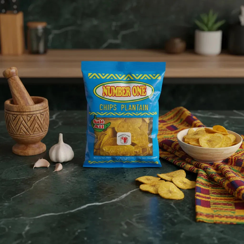 Chips de plantain à l'ail N°1 posées sur une table de cuisine avec ail frais et bol en accompagnement, snack savoureux d'épicerie salée.