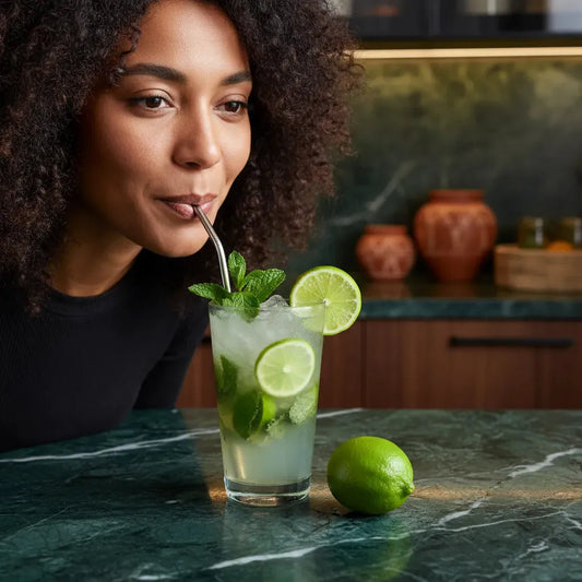 Femme dégustant une boisson au citron vert avec menthe, symbole de fraîcheur et de saveur unique. Agrume idéal pour cocktails.