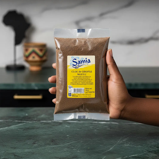 Main tenant un sachet de clous de girofle moulu SAMIA - Épice aromatique intense pour enrichir vos recettes sucrées et salées.