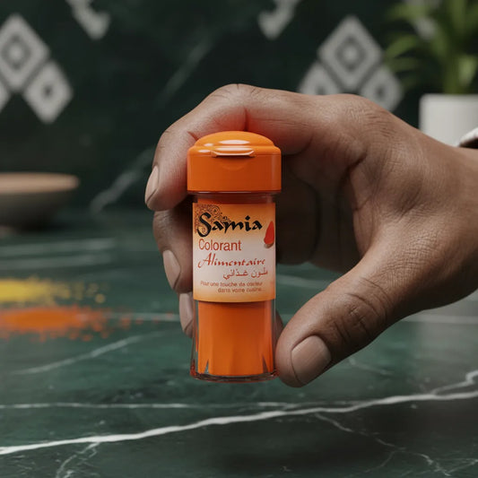 Main tenant un flacon de colorant alimentaire SAMIA sur fond de cuisine. Produit liquide idéal pour colorer plats et sauces.
