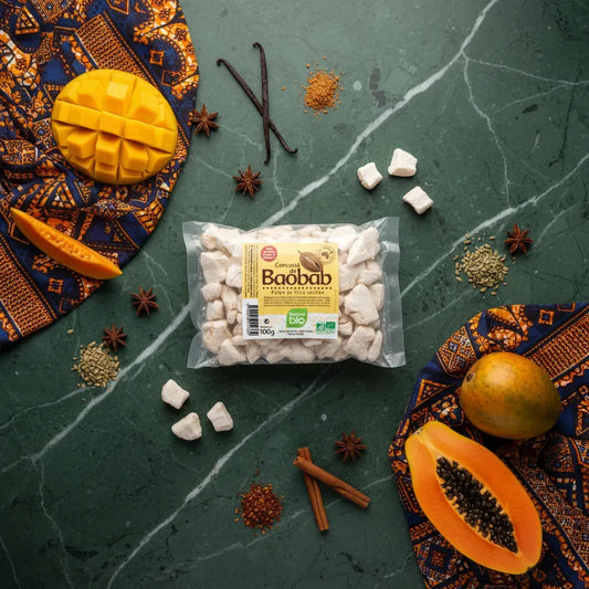 Sachet de concassé de baobab BIO RACINES entouré de fruits exotiques et épices, idéal pour enrichir plats sucrés avec une touche acidulée naturelle.