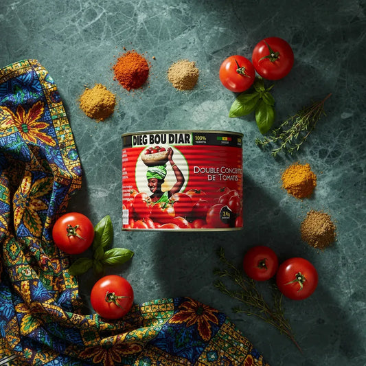 Concentré de tomate DIEG BOU DIAR entouré d'épices et tomates fraîches sur fond de marbre, parfait pour recettes savoureuses et épicées.