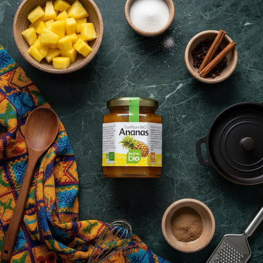 Pot de confiture ananas RACINES BIO entouré d'ingrédients naturels comme ananas, sucre et épices. Confiture bio au goût riche et authentique.