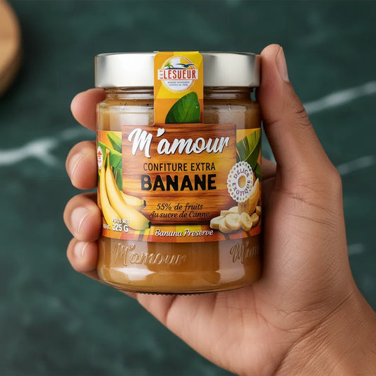 Main tenant un pot de confiture banane naturelle M'AMOUR, produit d'épicerie sucrée à base de fruits tropicaux.