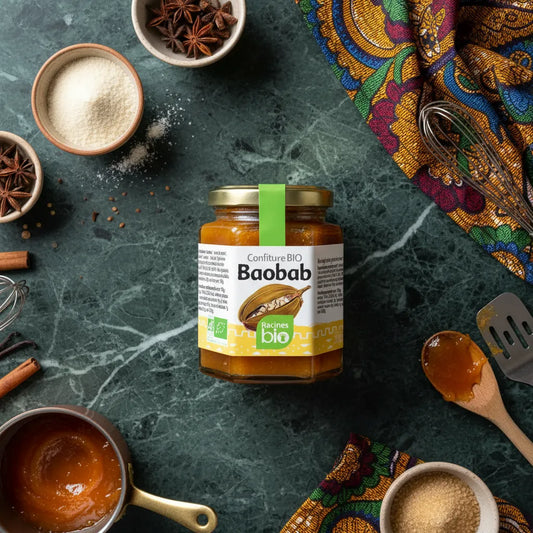 Pot de confiture baobab RACINES BIO sur table de cuisine avec épices et ustensiles, idéal pour recettes sucrées exotiques.