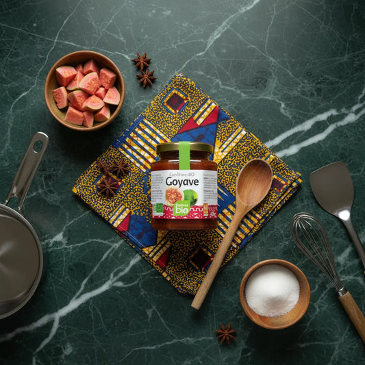 Confiture goyave RACINES BIO posée sur tissu coloré avec ingrédients naturels autour, illustrant son authenticité bio et artisanale.