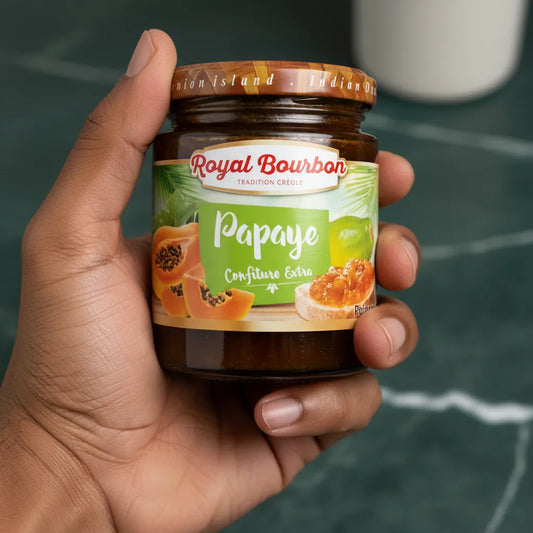 Main tenant un pot de confiture de papaye ROYAL BOURBON, produit d'épicerie sucrée aux saveurs exotiques et naturelles.