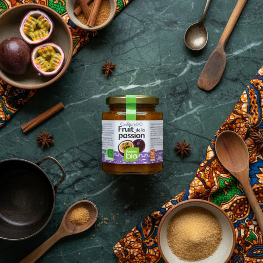 Pot de confiture fruit de la passion bio Racines entouré d'épices, sucre brut et fruits frais, idéal pour recettes exotiques sucrées.