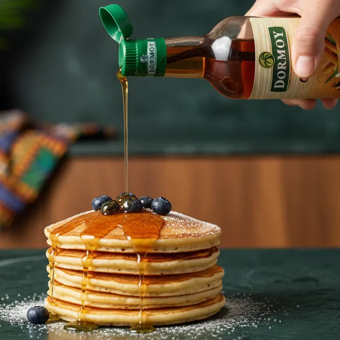 Versement de Sirop de Canne DORMOY sur pancakes aux myrtilles, sucrant naturel antillais pour sublimer petits-déjeuners et desserts gourmands.