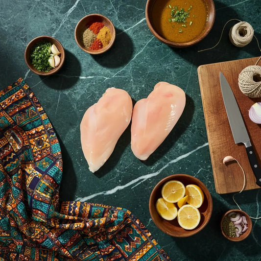 Filet de poulet Halal sur planche avec épices, citron et herbes, idéal pour recettes savoureuses. Texture tendre et juteuse mise en valeur.