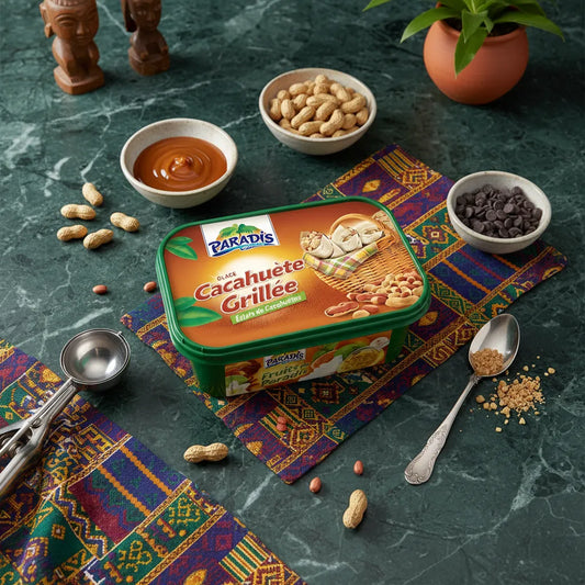 Bac de glace cacahuète grillée PARADIS GLACE entouré d’ingrédients comme cacahuètes, chocolat et caramel sur nappe colorée.