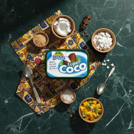 Bac de glace Super Coco Paradis Glace entouré d’ingrédients tropicaux comme noix de coco, mangue et sucre, sur fond de marbre vert. Glace coco exotique.