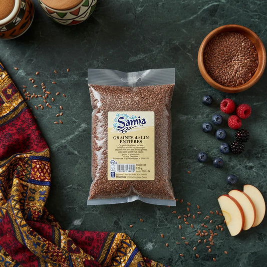 Sachet de graines de lin entières SAMIA posé sur une table avec fruits et tissu coloré, parfait pour agrémenter vos plats avec goût et croquant.