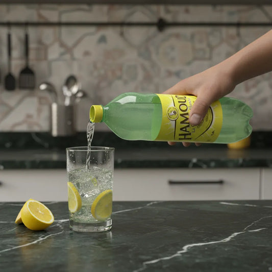 Versement de la boisson limonade HAMOUD dans un verre avec rondelles de citron, soda pétillant rafraîchissant pour la cuisine moderne.