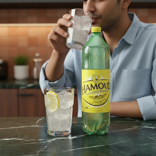 Homme dégustant la boisson limonade HAMOUD, soda rafraîchissant servi avec glaçons et citron, parfait pour un moment désaltérant.