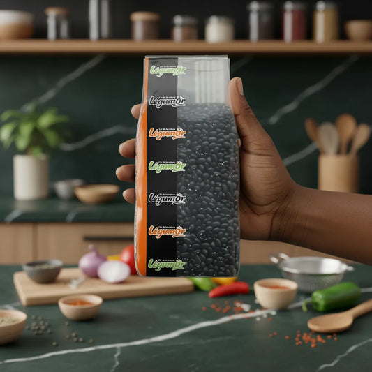 Main tenant un sachet de haricots noirs coco LEGUMOR dans une cuisine moderne, soulignant leur qualité et usage culinaire varié.