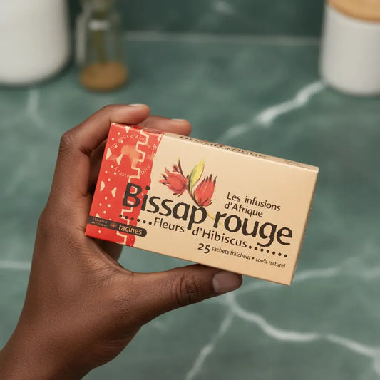 Boîte d'infusion Bissap Hibiscus RACINES tenue en main, mettant en avant son format pratique et ses bienfaits naturels à base d'hibiscus.