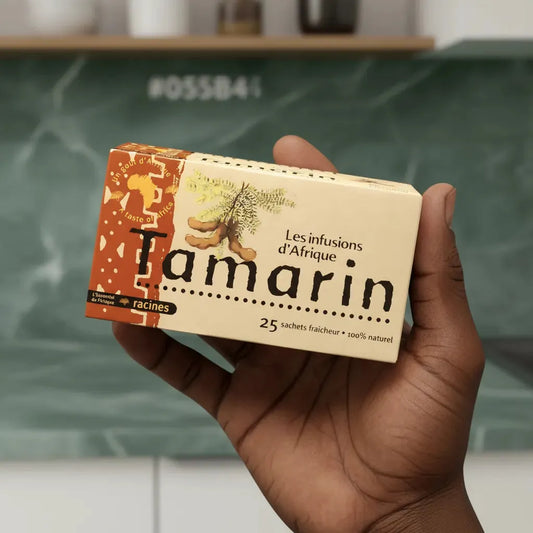 Main tenant une boîte d'infusion RACINES tamarin d'Afrique, 25 sachets fraîcheur, infusion naturelle au goût unique.