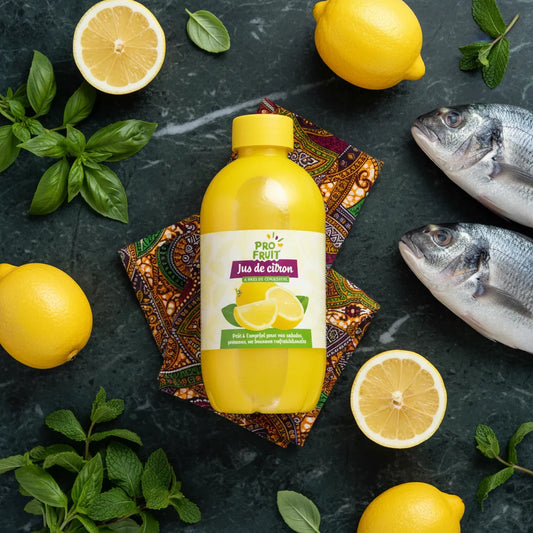 Bouteille de jus de citron concentré PROFRUIT entourée de citrons frais, poissons et herbes. Ingrédient essentiel pour plats de fruits de mer.