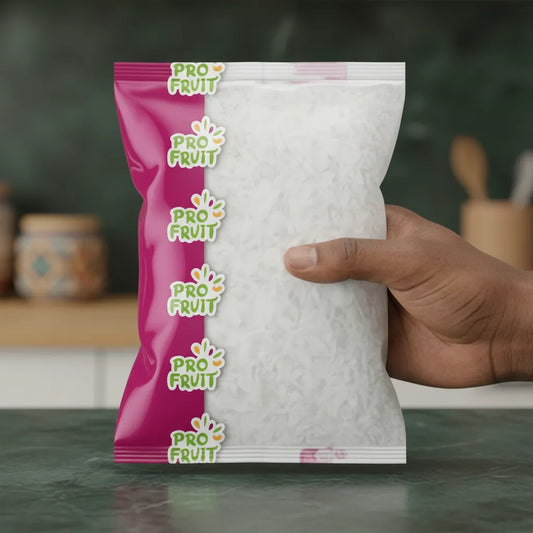 Main tenant un sachet de coco râpée PROFRUIT, pulpe de noix de coco surgelée visible à travers l'emballage, idéale pour la pâtisserie.