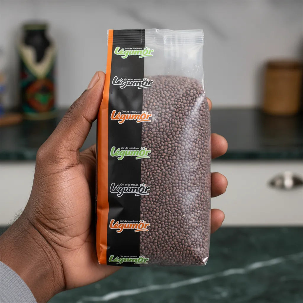 Main tenant un sachet de lentilles rouges entières LEGUMOR en gros plan. Produit d'épicerie salée pratique pour cuisine quotidienne et équilibrée.