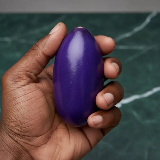 Safou entier tenu en main, mettant en valeur sa taille, sa forme ovale et sa couleur violette caractéristique, fruit frais d’Afrique.