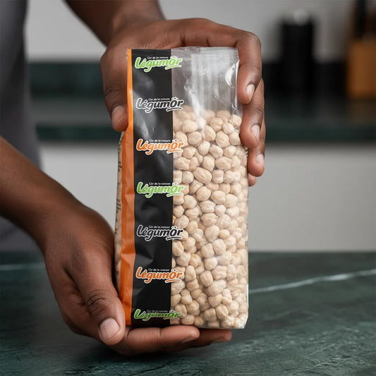 Sachet de pois chiches 9mm LEGUMOR tenu en main, montrant la qualité et la taille uniforme des grains secs.