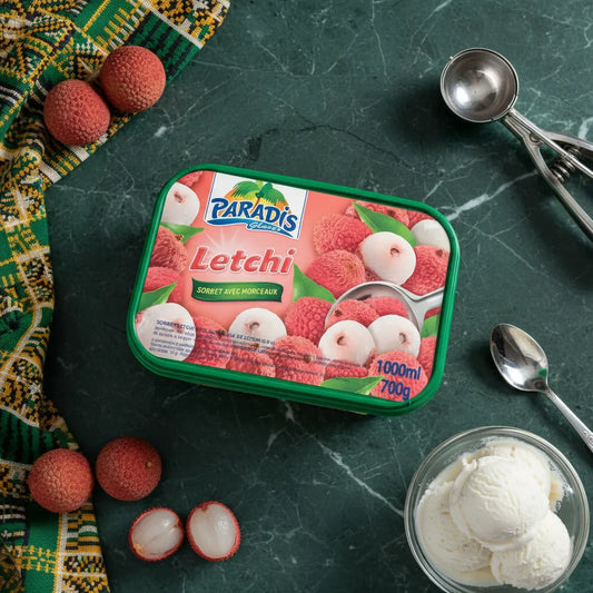Bac de Glaces Letchi - Paradis Glace posé sur table avec fruits letchi frais et ustensiles, sorbet tropical en épicerie sucrée.