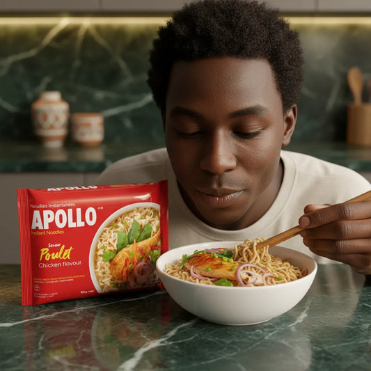 Homme dégustant un bol de nouilles poulet APOLLO avec baguettes, à côté de l’emballage rouge. Repas rapide et savoureux en épicerie salée.