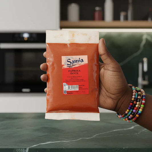 Paprika SAMIA - Épice Aromatique tenue en main dans une cuisine moderne, idéale pour relever vos recettes salées.