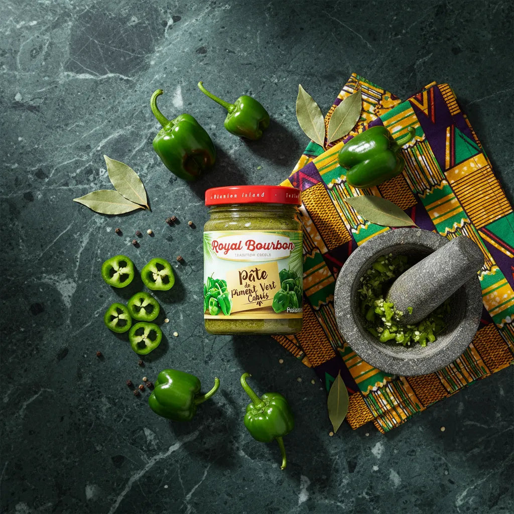 Pâte de piment cabris vert Royal Bourbon entourée de piments frais, feuilles de laurier et mortier, idéale pour la cuisine créole épicée.