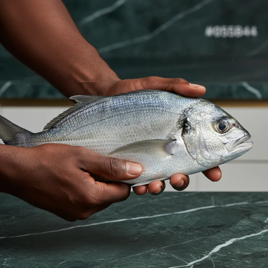 Carangue trevally poisson tenu à la main, texture ferme et brillante, idéal pour recettes grillées ou en sauce, riche en protéines.