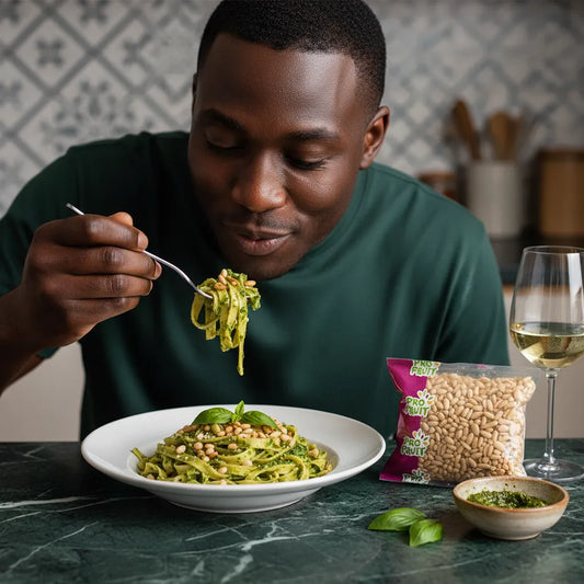 Homme dégustant des pâtes au pesto garnies de pignons de pin PROFRUIT, graines comestibles à texture tendre parfaites pour la cuisine italienne.
