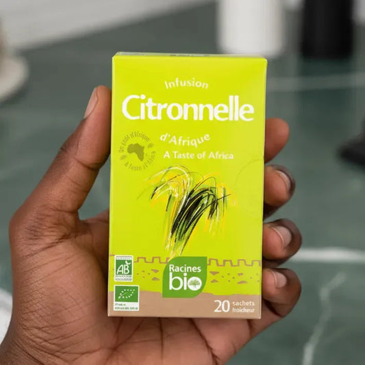Main tenant une boîte d'infusion BIO Afrique citronnelle Racines. Produit naturel, goût vivifiant et certifié agriculture biologique.