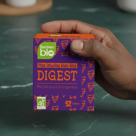 Main tenant une boîte d'infusion bien-être Digest BIO Racines, 10 sachets, certifiée AB, idéale pour digestion douce et naturelle.