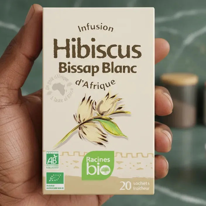 Main tenant une boîte d'infusion hibiscus blanc BIO RACINES, tisane bio africaine aux arômes délicats, certifiée agriculture biologique.