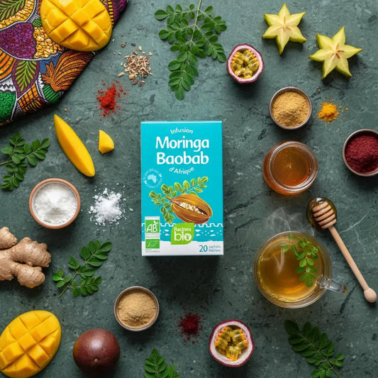 Infusion Baobab Moringa BIO Racines entourée d'ingrédients naturels comme mangue, gingembre et fruits exotiques, sur fond vert élégant.