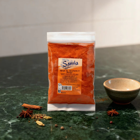 Sachet de Raz el hanout rouge SAMIA posé sur plan de travail avec épices entières, parfait pour cuisine orientale maison.